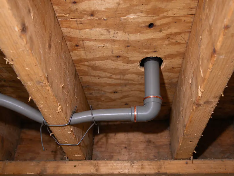 Gray polybutylene supply pipe with copper crimp rings in a crawl space