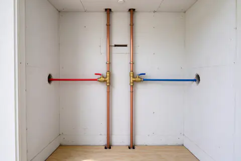 Open utility closet in a condo unit with new copper riser connections, ball valves and red and blue PEX branch lines
